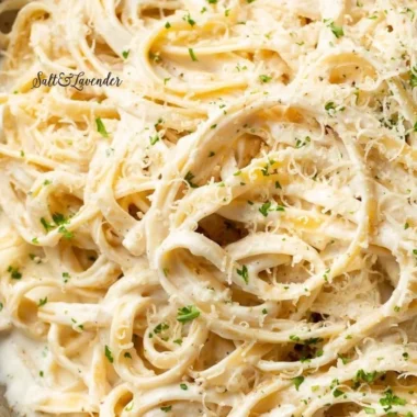 Homemade Alfredo sauce in a white bowl, garnished with parsley.