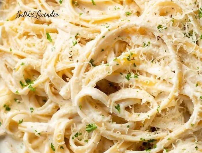 Homemade Alfredo sauce in a white bowl, garnished with parsley.