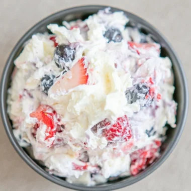 Delicious cheesecake salad served in a bowl with fresh fruit and toppings.