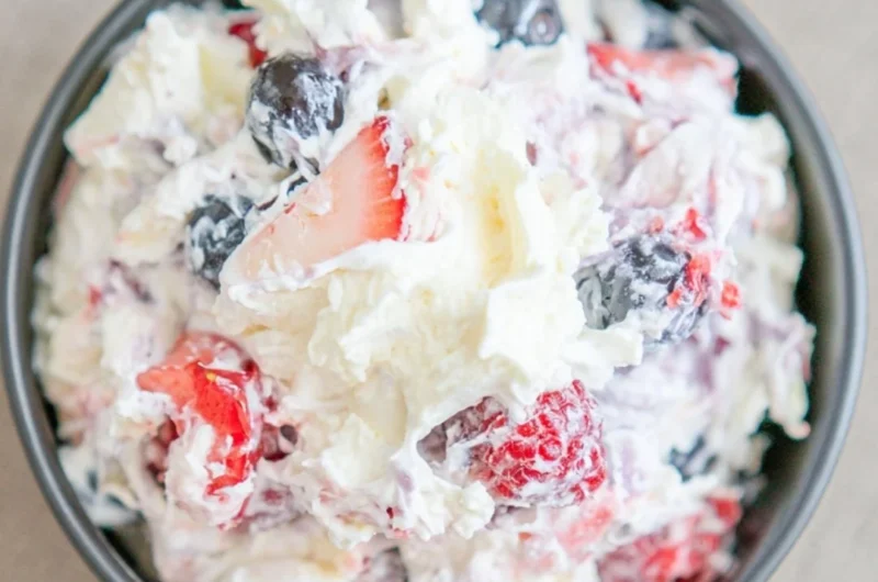 Delicious cheesecake salad served in a bowl with fresh fruit and toppings.