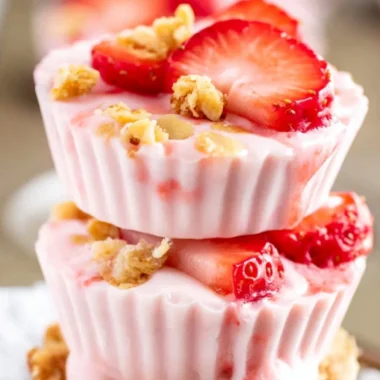 A bowl of frozen strawberry yogurt bites topped with fresh strawberries