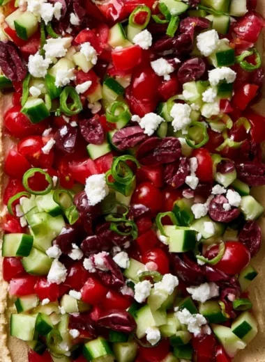 Delicious layered Greek dip served with pita chips and fresh vegetables