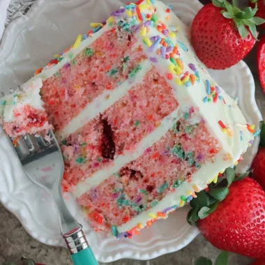 Slice of Strawberry Funfetti Cake with colorful sprinkles and fresh strawberries