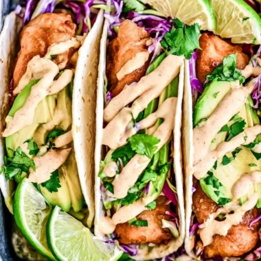 Cozy Baja fish tacos served with fresh toppings and lime wedges.