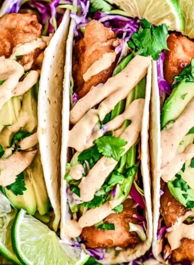 Cozy Baja fish tacos served with fresh toppings and lime wedges.