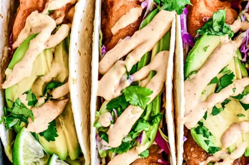 Cozy Baja fish tacos served with fresh toppings and lime wedges.