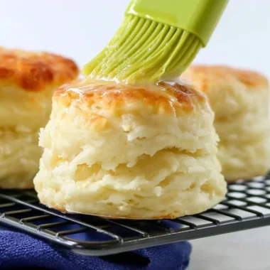Fluffy self-rising flour biscuits served warm on a rustic wooden table.