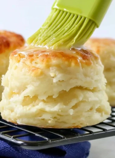 Fluffy self-rising flour biscuits served warm on a rustic wooden table.