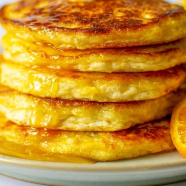 Cozy orange ricotta pancakes stacked with syrup and orange zest garnish