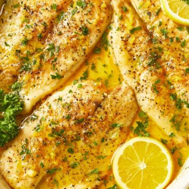 Oven baked tilapia served on a plate with fresh herbs and lemon slices