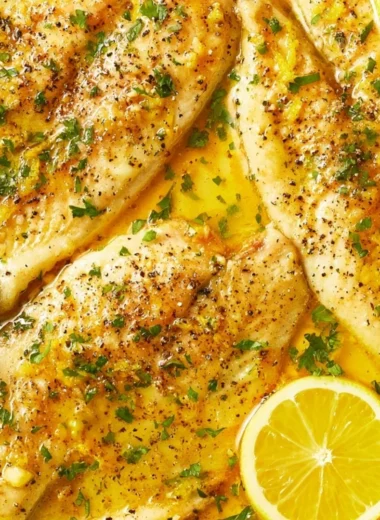 Oven baked tilapia served on a plate with fresh herbs and lemon slices