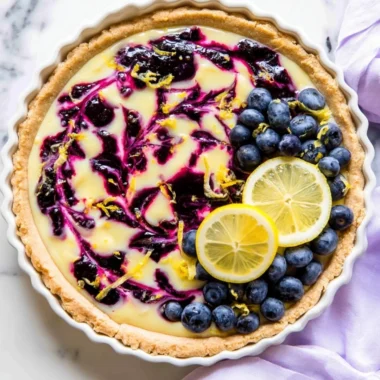 Creamy lemon tart with a drizzle of blueberry sauce on top