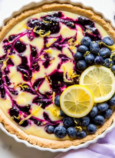 Creamy lemon tart with a drizzle of blueberry sauce on top