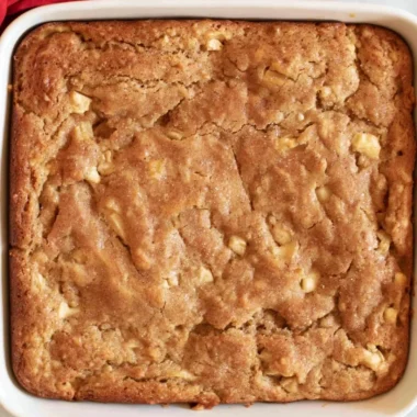 Delicious Amish apple cake with apples and spices served on a wooden table.