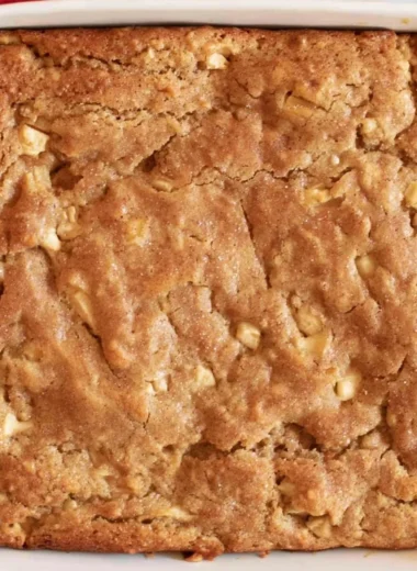Delicious Amish apple cake with apples and spices served on a wooden table.